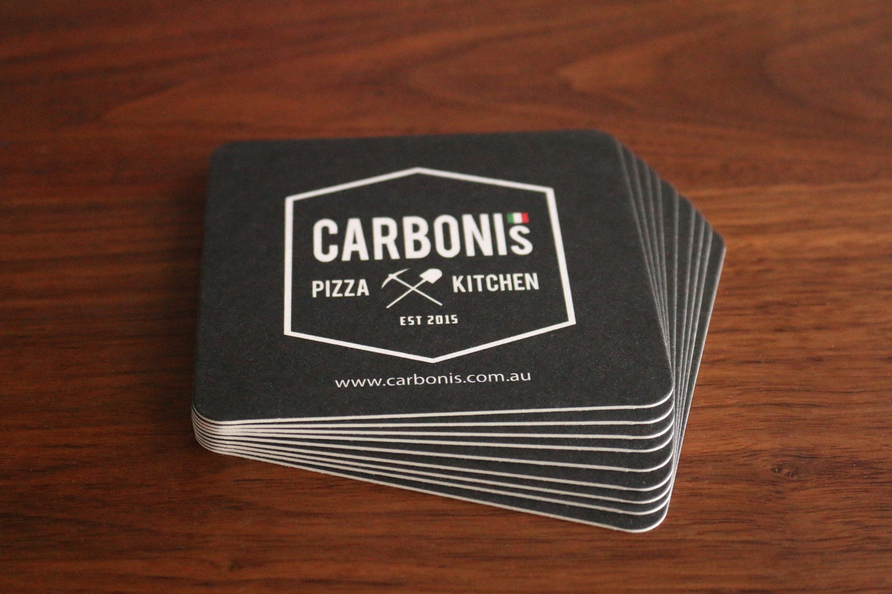 A stack of custom printed square drink coasters on coasterboard