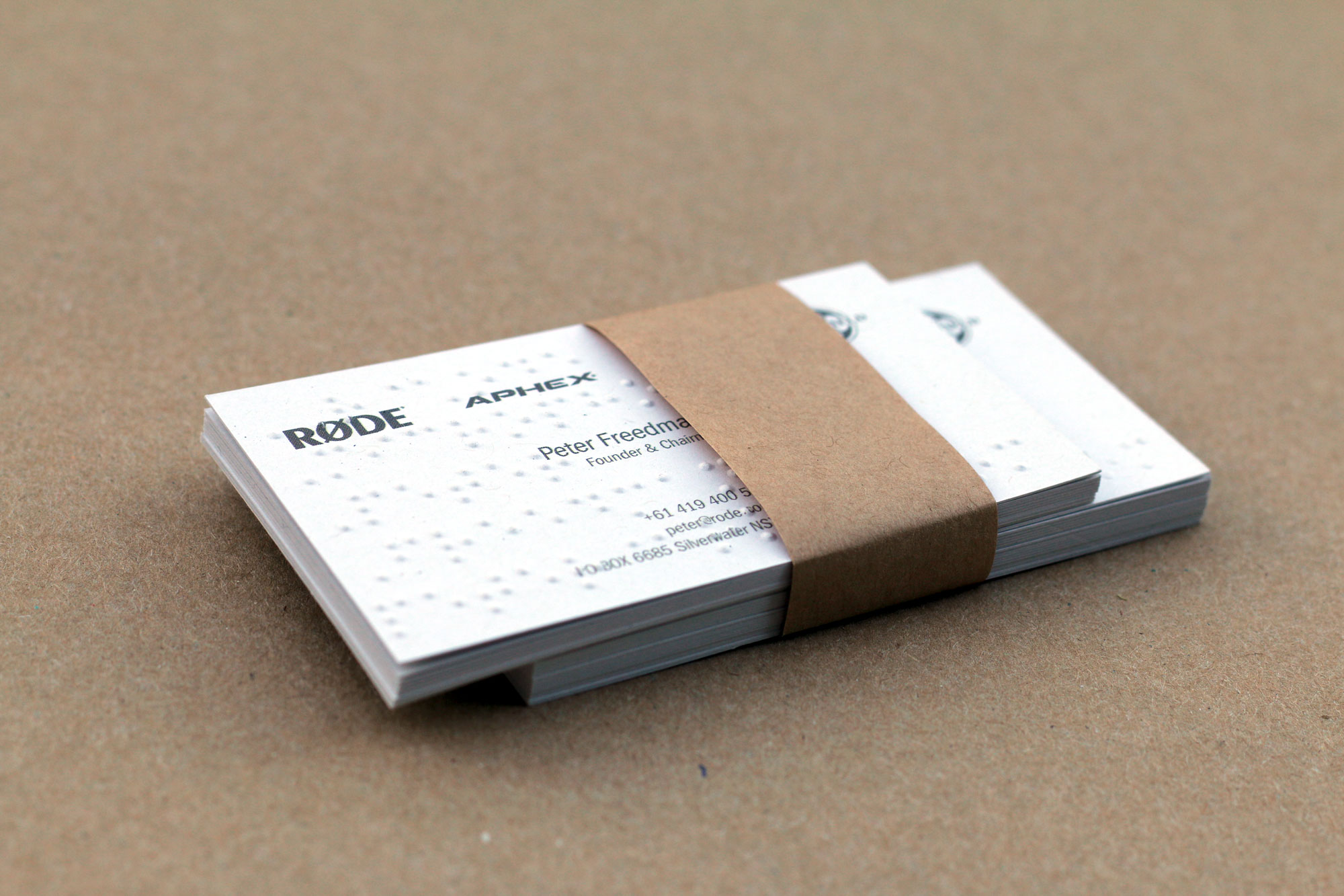 Stack of business cards with raised braille dots, wrapped with a recycled paper band